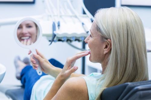 A woman smiling while checking her dental crown in Cloverdale, WA